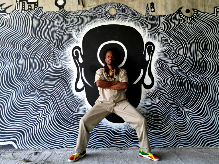 artiste papyon posant contre un mur avec un dessin e nnoir en blanc